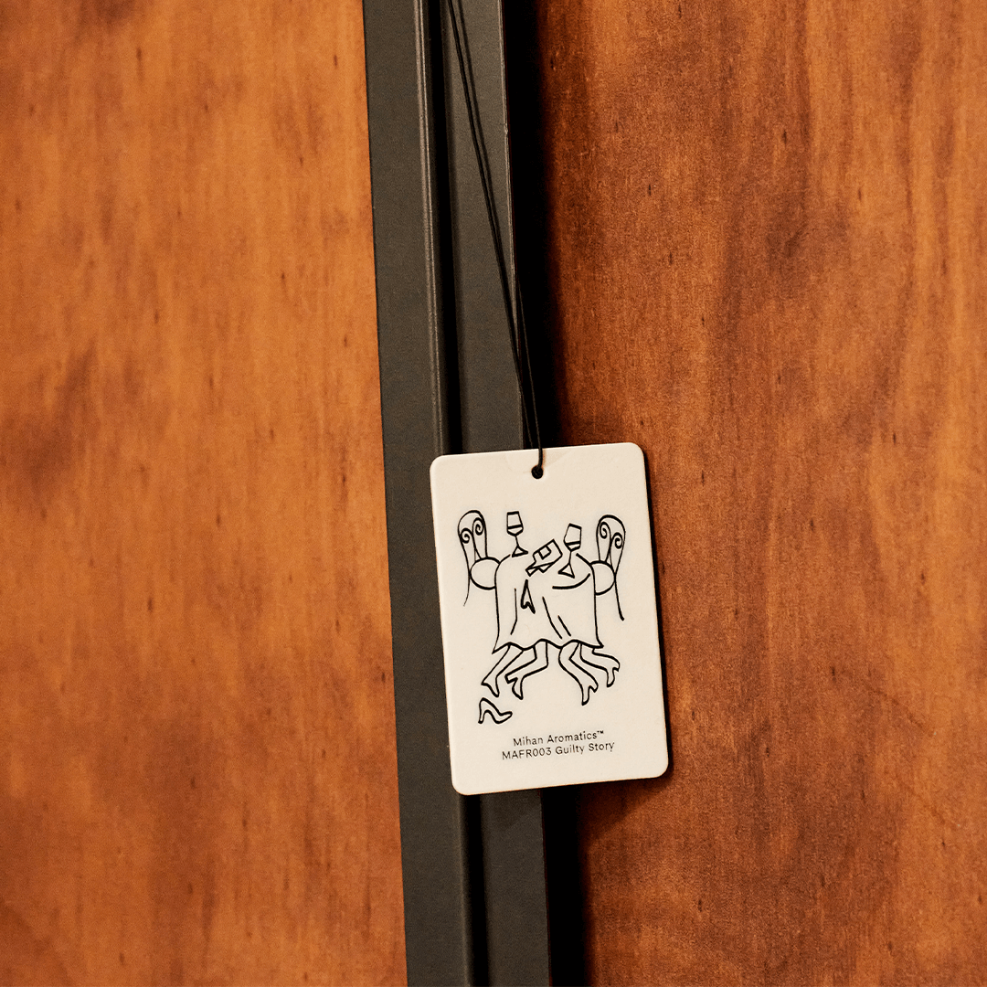 Guilty Story Air Fragrance Card hanging on a wooden surface, designed to enhance the scent in car, wardrobe, or luggage.
