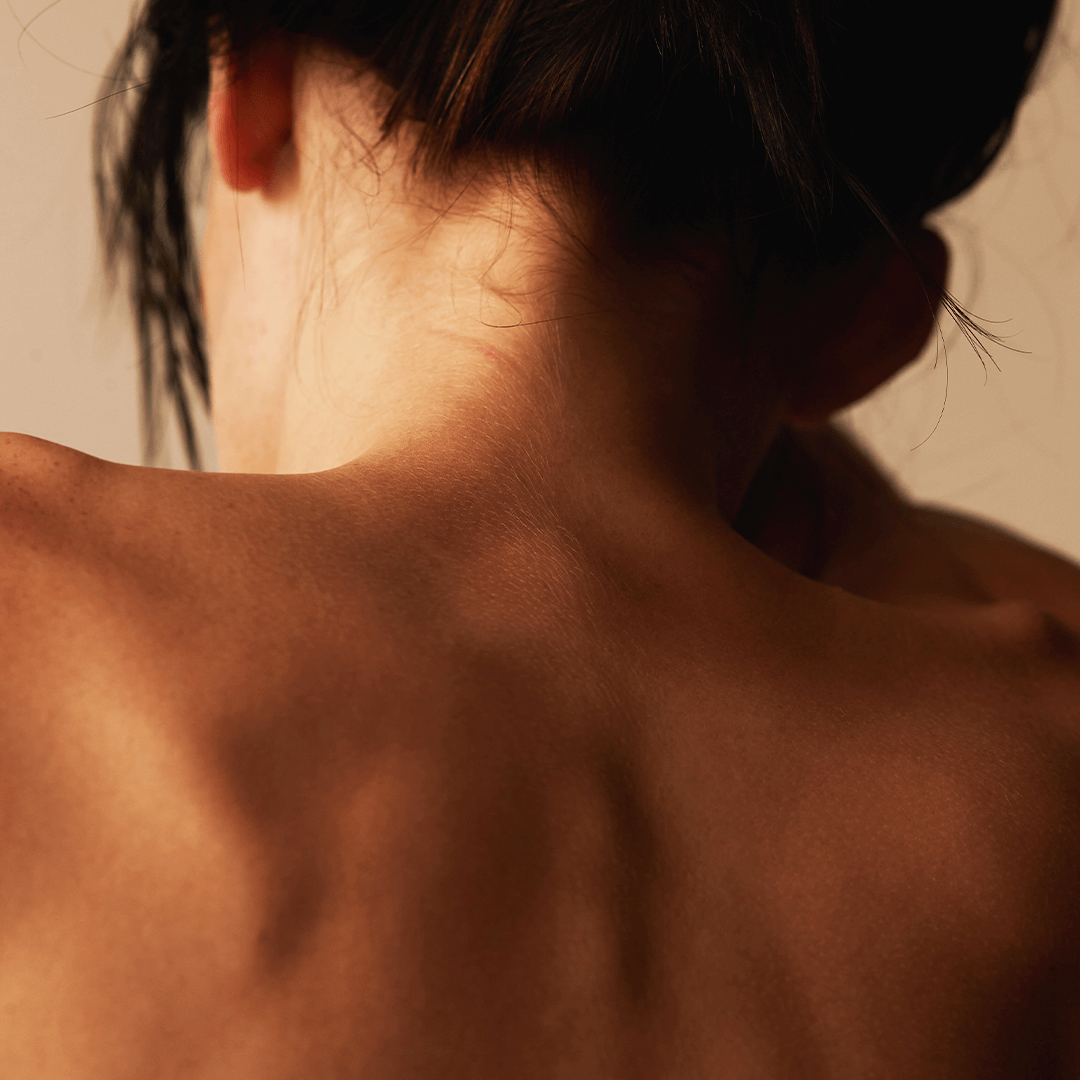 Close-up of the back of a person with a soft focus, showcasing smooth skin and a natural hairstyle.