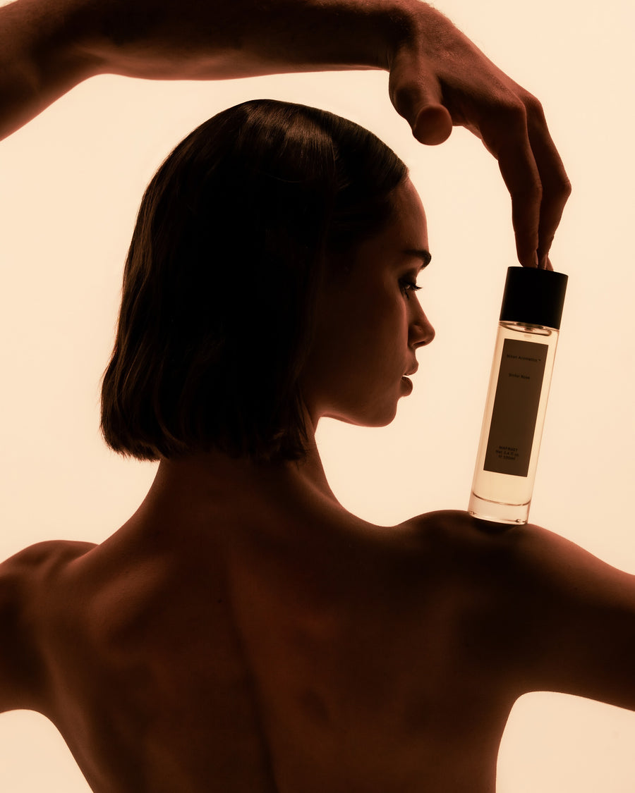 Model in profile balancing a Mihan Aromatics Sinful Rose parfum bottle on her shoulder