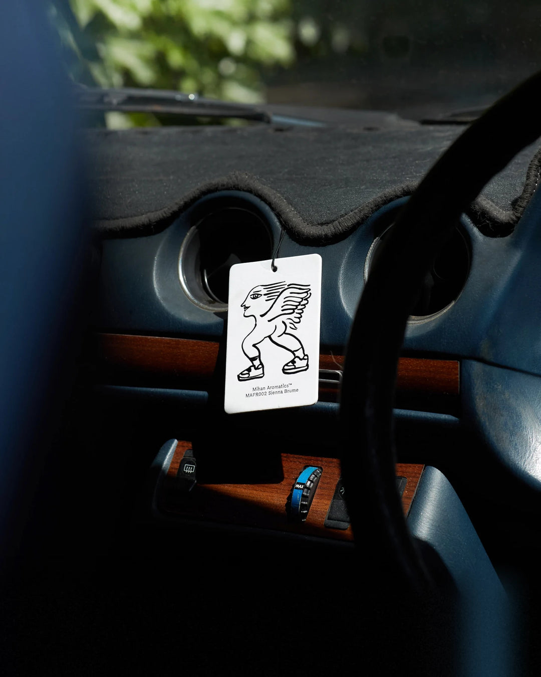 A Mihan Aromatics air fragrance card hanging in a car