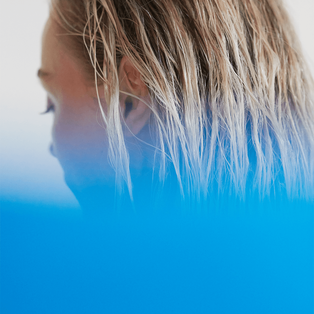 Close-up of a woman with wet, wavy blonde hair, showcasing a serene and relaxed atmosphere.