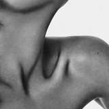 Artistic close-up of a neck and shoulder showcasing soft curves and shadows in monochrome.