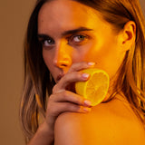 Model holding a cut lemon to her lips in amber light, Mihan Aromatics Series Three campaign