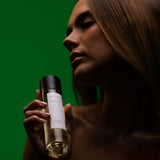 Model in profile holding a Mihan Aromatics Eucalyptus Bloom parfum 100ml bottle against a deep green backdrop