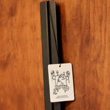 Mihan Aromatics Guilty Story Air Fragrance hanging from a black handle on a timber door