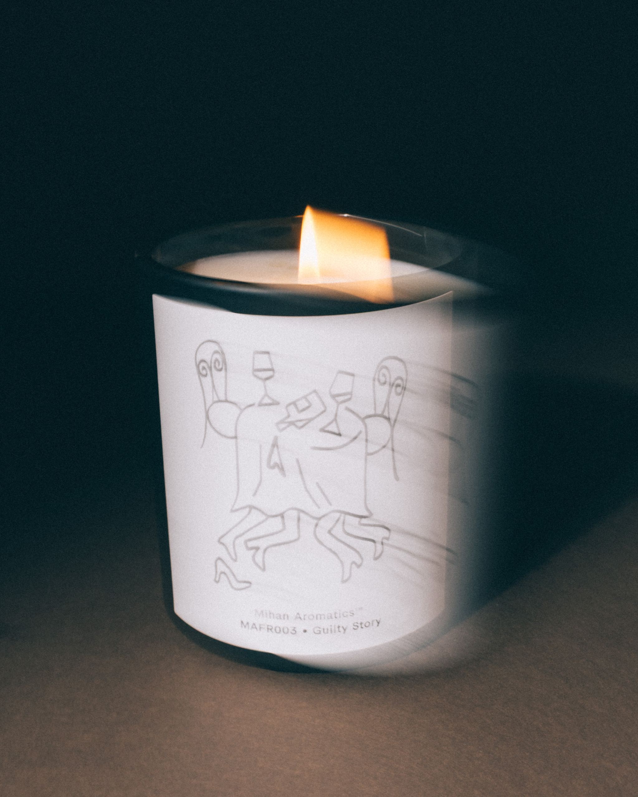 Lit Mihan Aromatics Guilty Story candle with soft motion blur in low light