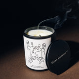 Mihan Aromatics Guilty Story candle with its lid set aside and a trail of smoke rising from the wick