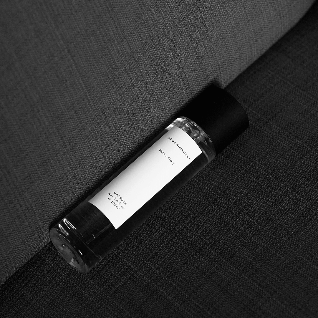Guilty Story Parfum bottle placed on a textured gray surface, exuding warmth and luxury.