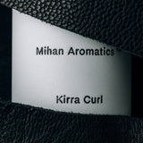 Close view of the Mihan Aromatics Kirra Curl parfum label framed by black leather