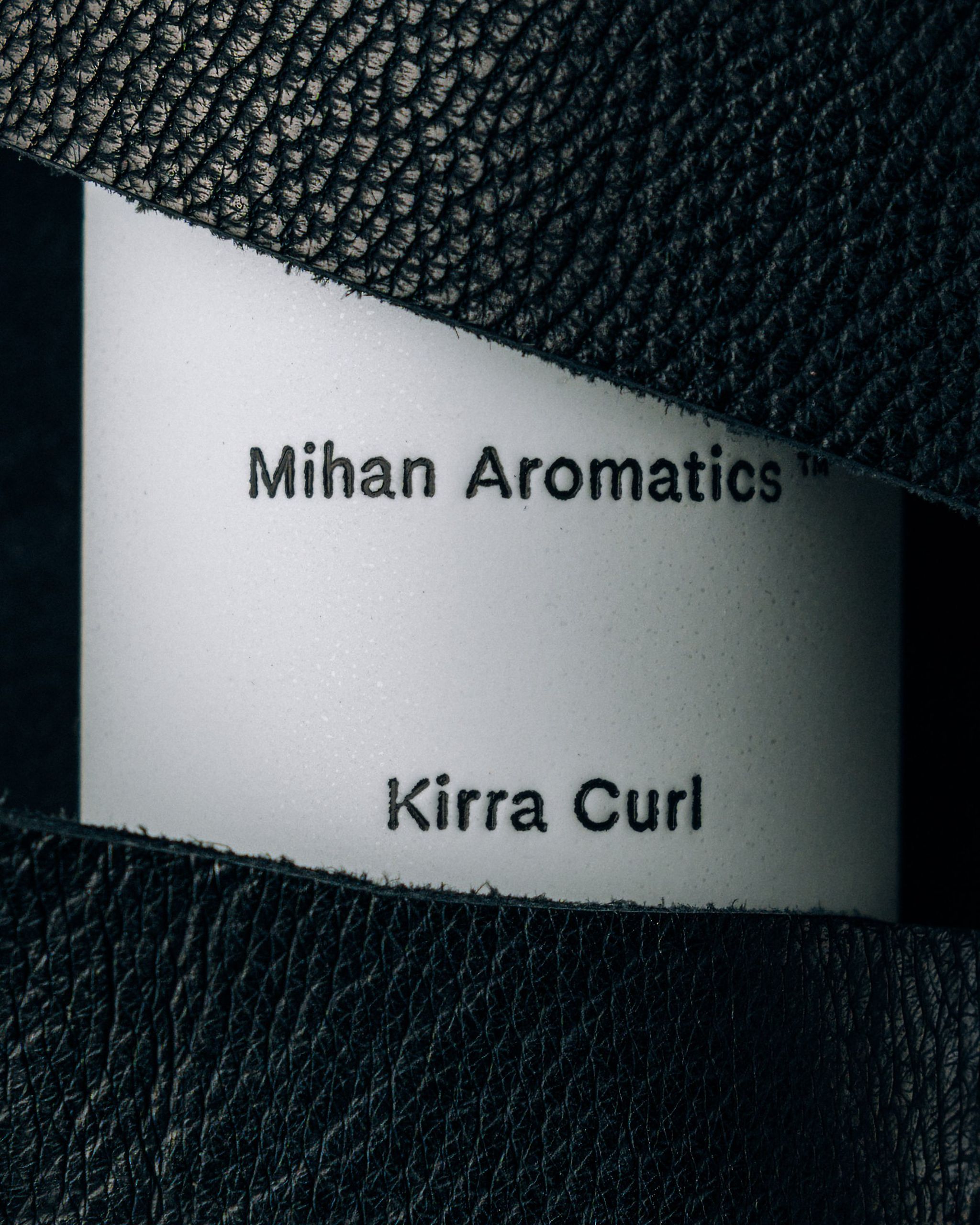 Close view of the Mihan Aromatics Kirra Curl parfum label framed by black leather