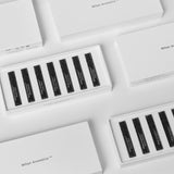 Flat lay of several Mihan Aromatics Discovery Set boxes, open and closed, on pale grey