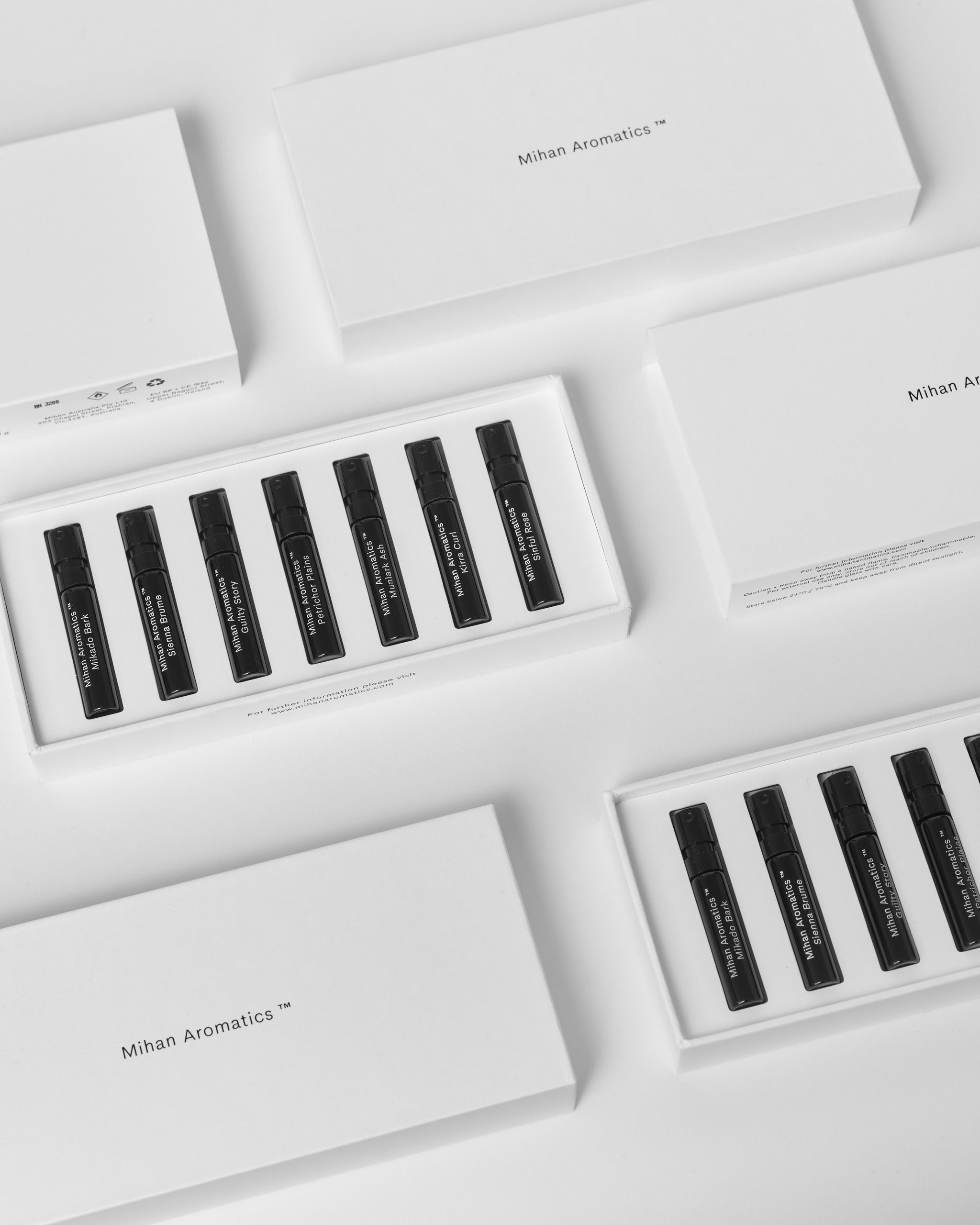 Flat lay of several Mihan Aromatics Discovery Set boxes, open and closed, on pale grey