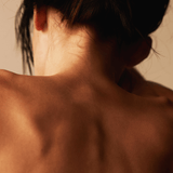Close-up of the back of a person showcasing skin texture and hair, emphasizing natural beauty.