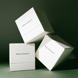 Stacked white Mihan Aromatics candle gift boxes on a deep green backdrop