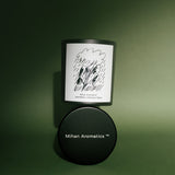 Mihan Aromatics Petrichor Plains candle resting on its black lid against a green backdrop