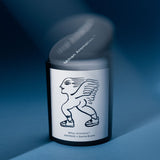 Mihan Aromatics Sienna Brume candle with its lid lifting away in motion on a blue backdrop