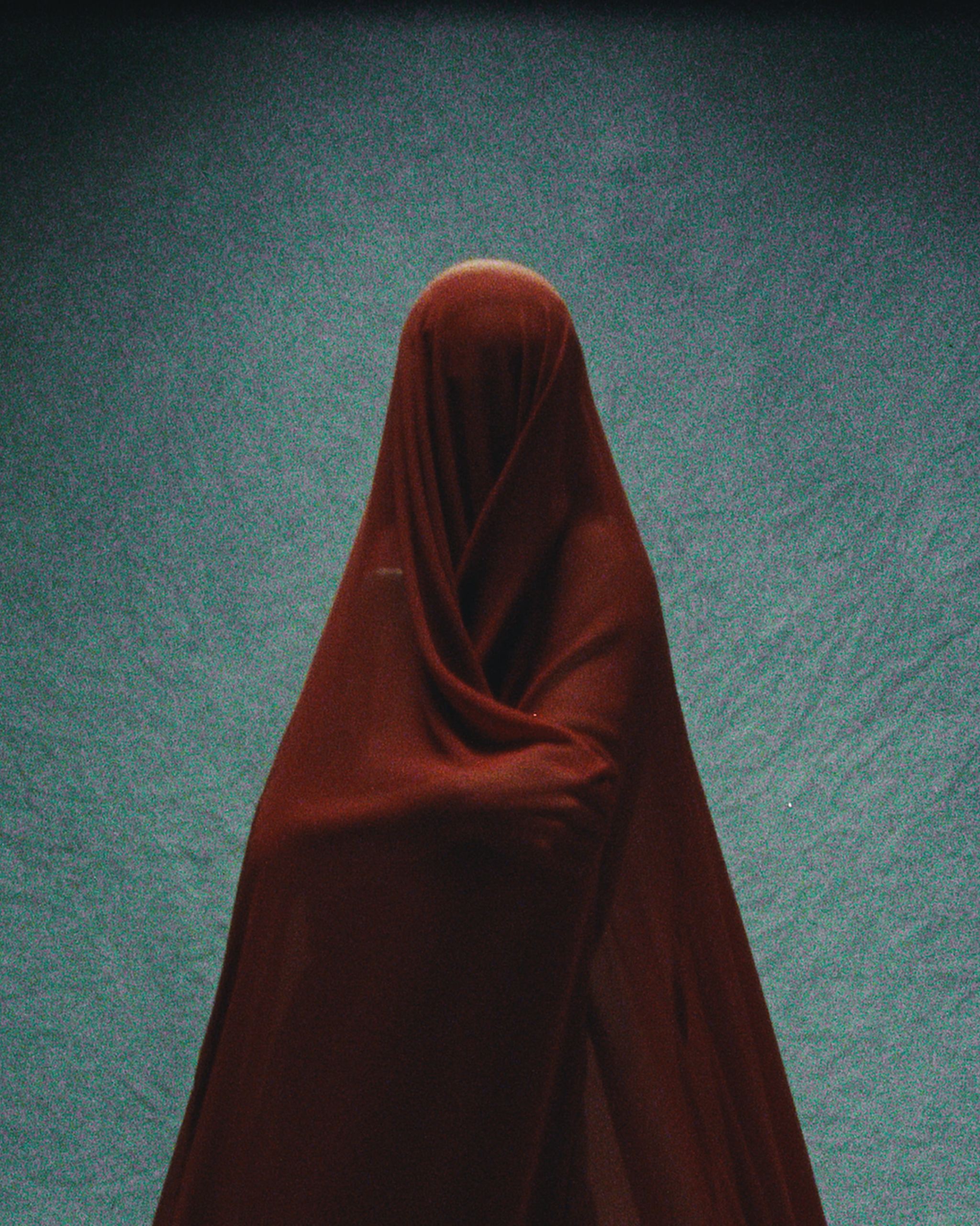 Figure veiled in deep red cloth against a teal backdrop, Mihan Aromatics Sinful Rose parfum campaign