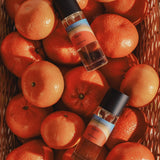 Two Mihan Aromatics x Kip&Co Soul Nectar parfum bottles resting in a basket of mandarins