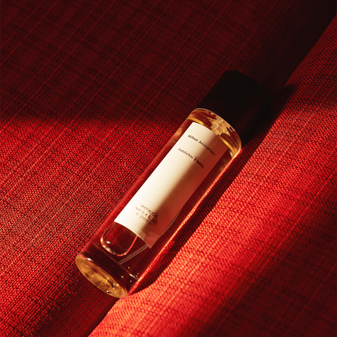 Petrichor Plains Parfum by Mihan Aromatics, showcasing the elegant bottle against a warm red background.