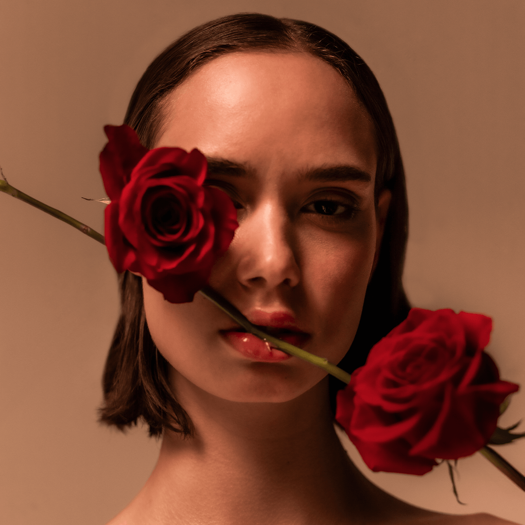 A woman with red roses, evoking the romantic essence of Sinful Rose Parfum by Mihan Aromatics.