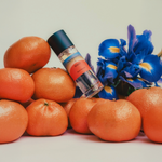 Soul Nectar Parfum displayed with fresh oranges and vibrant blue irises, evoking warmth and life.